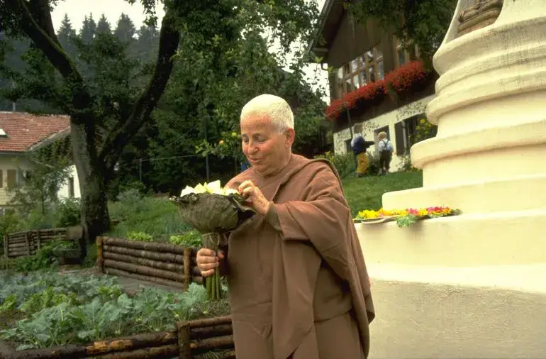Buddhistische Nonne hält Blumen im Garten.