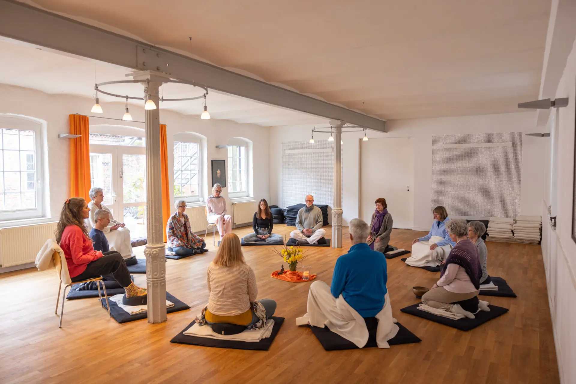 Meditationsgruppe sitzt gemeinsam im Kreis.