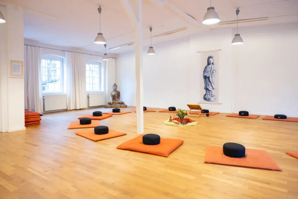 Heller Meditationsraum mit kreisförmig angeordneten Sitzkissen.