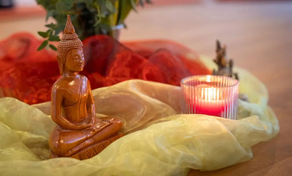 Buddhafigur und Kerze in meditativer Atmosphäre.