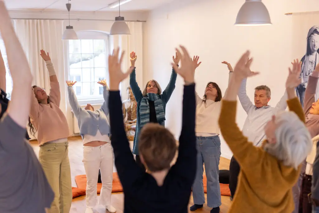 Menschen bei gemeinsamer Bewegungsübung im Seminarraum.