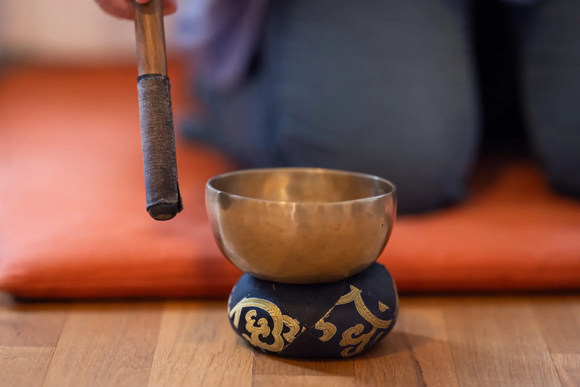 Klangschale mit Schlägel auf Meditationskissen.