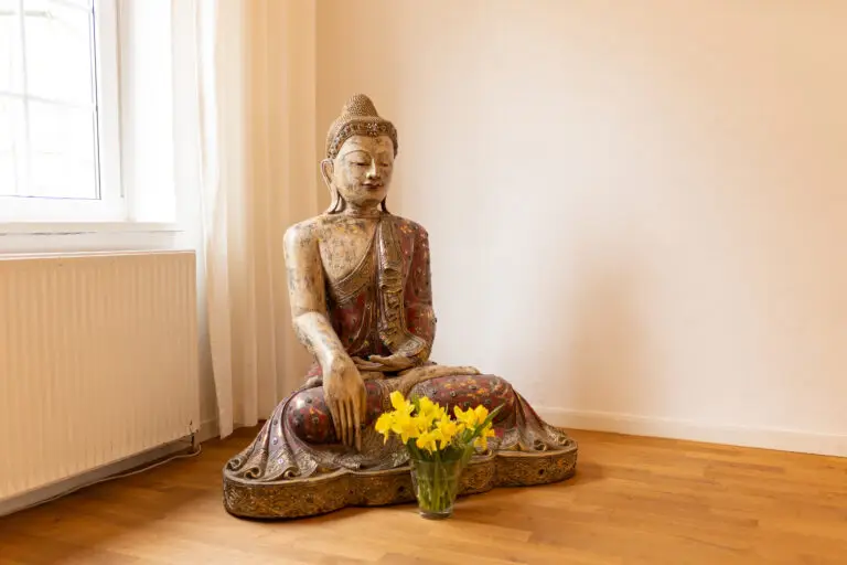 Buddhafigur mit gelben Blumen im Raum.