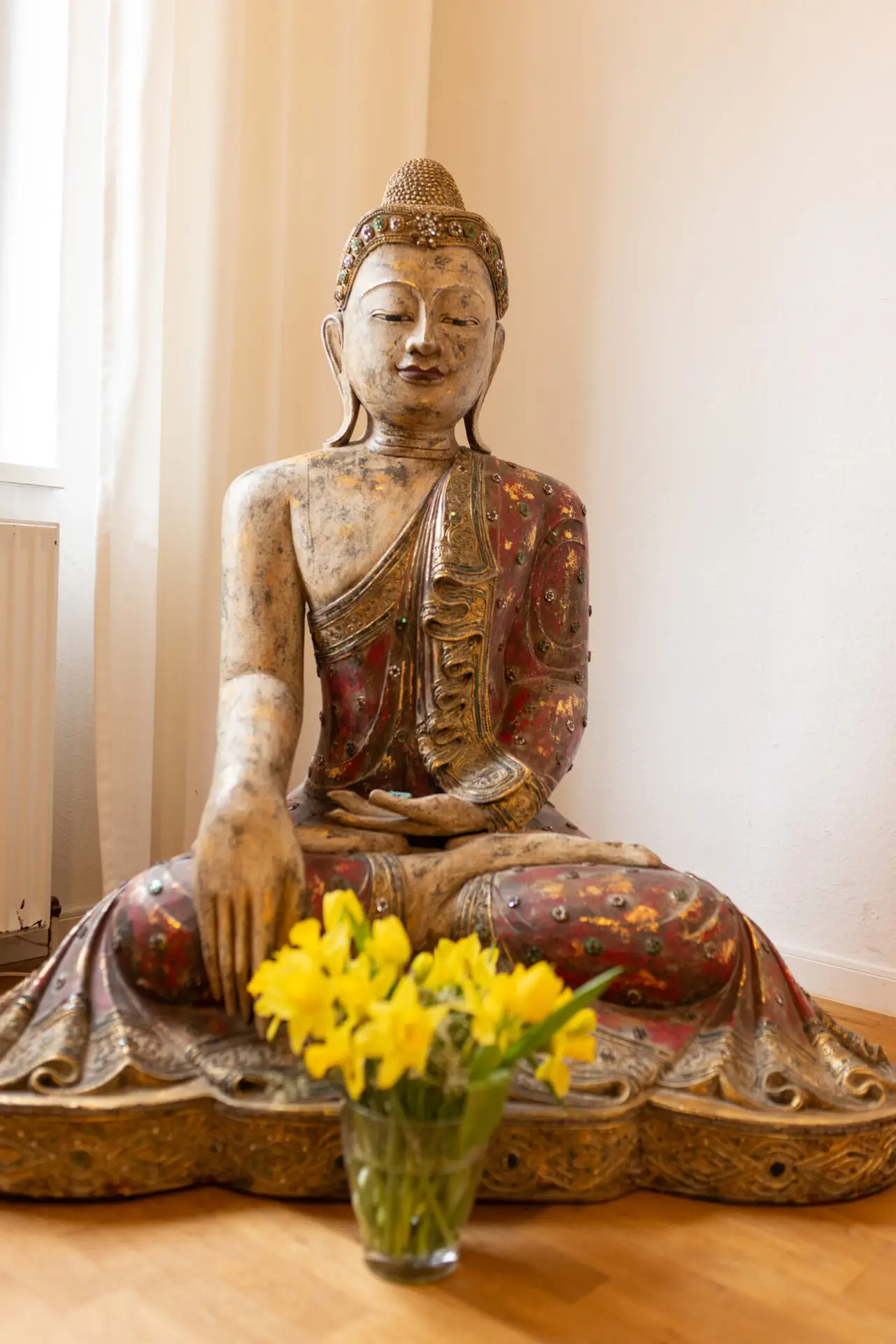 Buddhafigur mit gelben Blumen im Vordergrund.gg