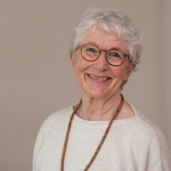 Lächelnde Frau mit Brille und weißem Haar.