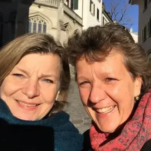 Zwei lächelnde Frauen bei sonnigem Stadtspaziergang.